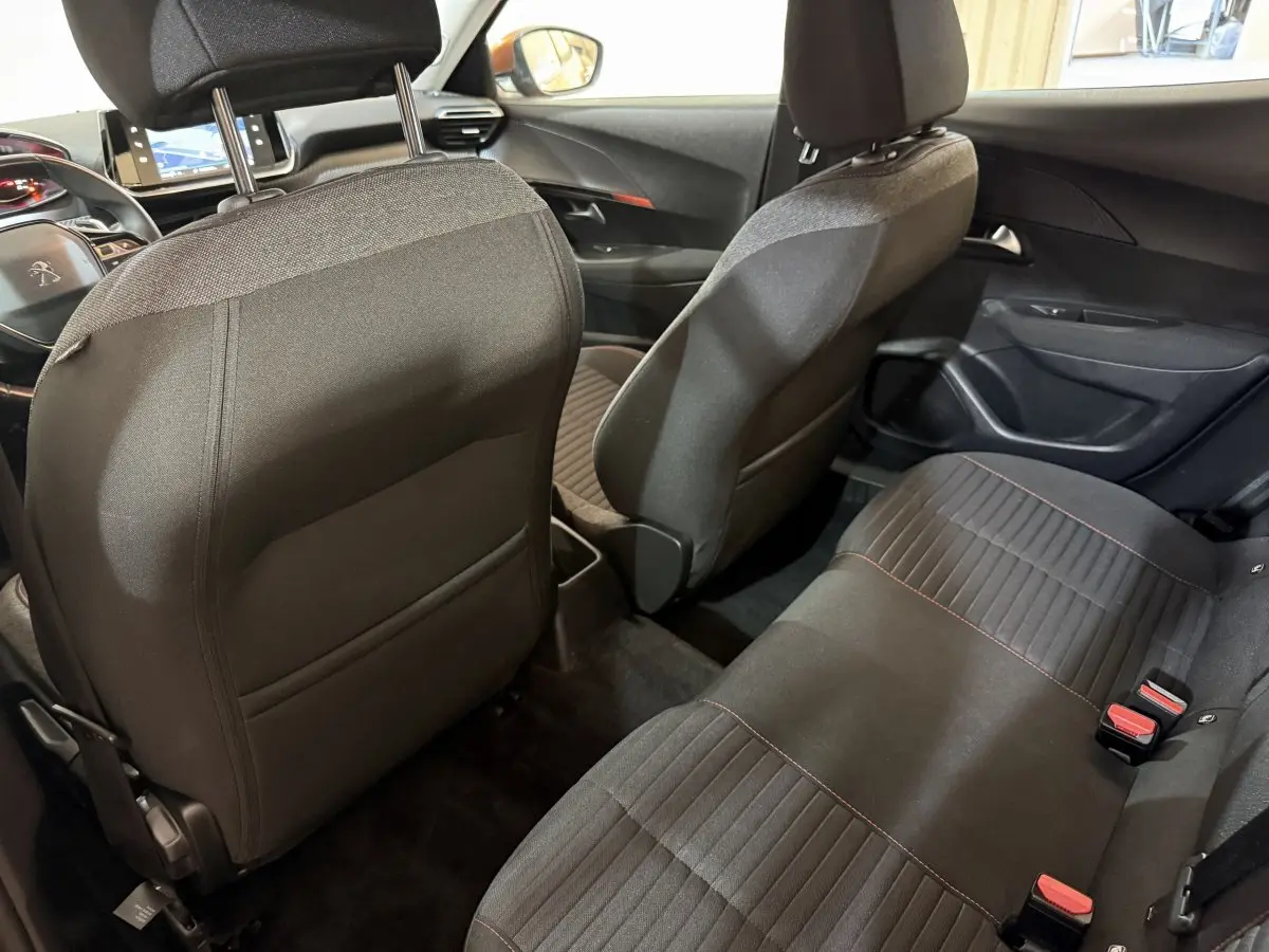 Vue intérieure arrière du Peugeot 2008 2022, sièges tissu noirs avec surpiqûres rouges et tableau de bord visible.