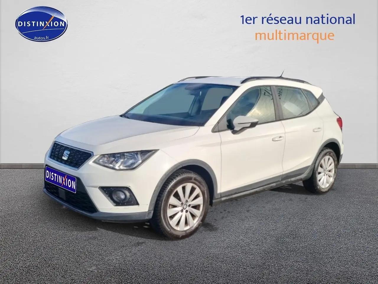 SEAT Arona blanc vue 3/4 avant droit, avec jantes alliage et barres de toit noires visibles.