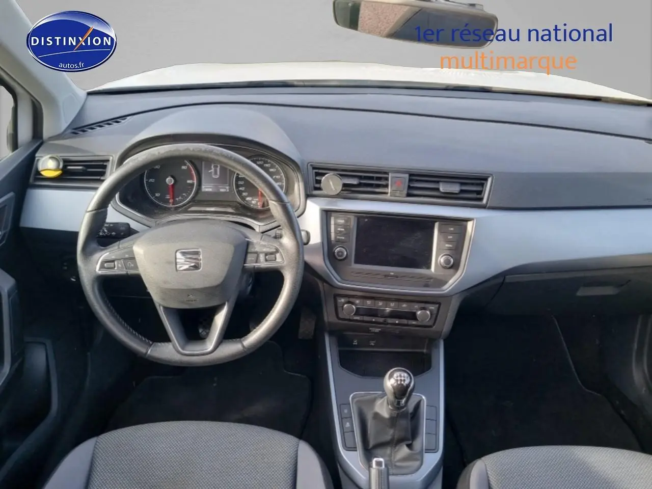 Vue intérieure du tableau de bord et volant cuir du SEAT Arona 1.6 TDI 115 style, avec écran tactile et levier de vitesse manuel.