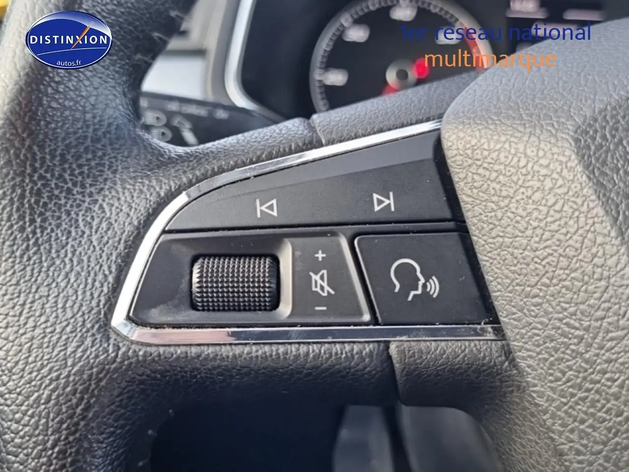 Gros plan sur les commandes audio et vocales sur le volant cuir d'une SEAT Arona blanche de 2019.