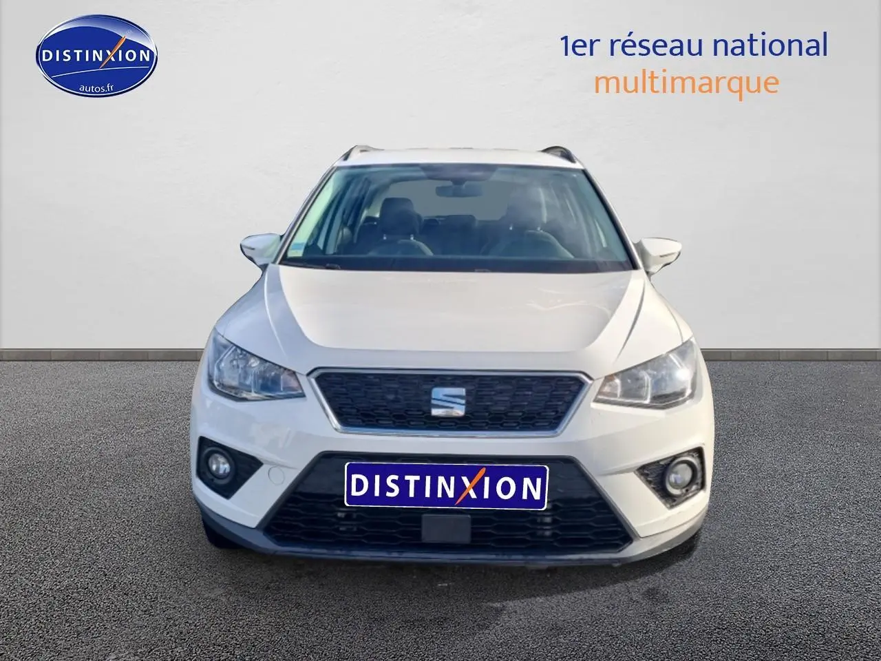 Vue frontale d'un SEAT Arona blanc 2019 avec calandre noire et phares halogènes allumés.