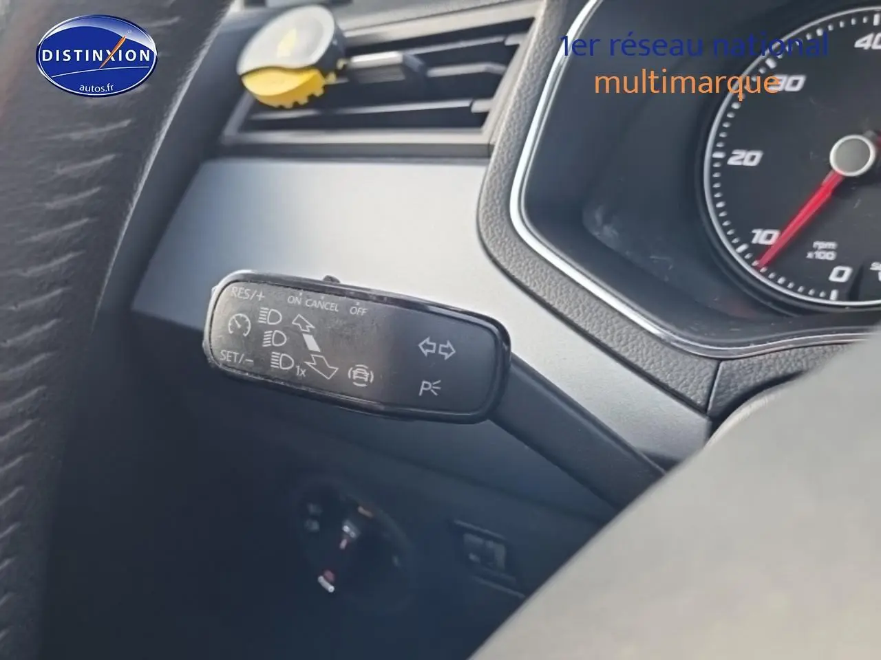 Gros plan sur la manette de commande multifonction noire à gauche du volant dans l'habitacle d'une SEAT Arona blanche.