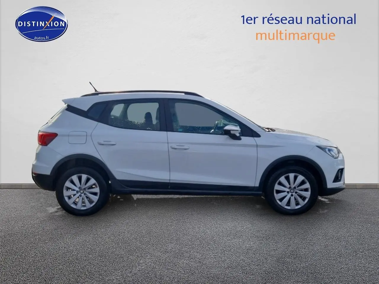 Vue de profil côté gauche d’un SEAT Arona blanc 2019 avec jantes alu et barres de toit noires.