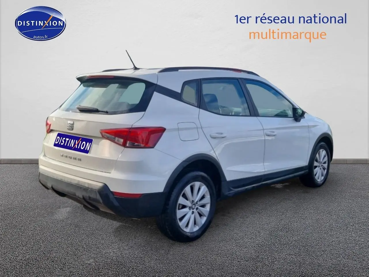 Vue 3/4 arrière droite d'un SEAT Arona blanc avec barres de toit et jantes alu.