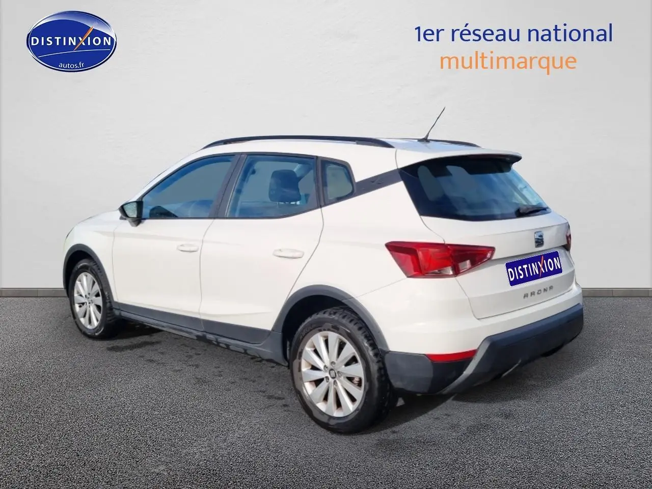 SEAT Arona blanc vue 3/4 arrière droit, avec barres de toit et jantes alliage visibles.
