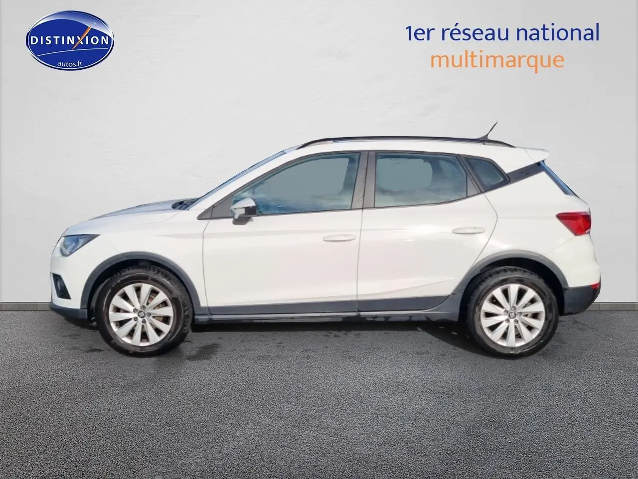 Vue latérale droite d'une SEAT Arona blanche avec jantes alliage et barres de toit noires.