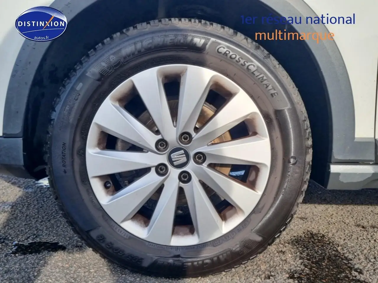 Gros plan sur la roue avant gauche d’un SEAT Arona blanc avec jante alu et pneu Michelin CrossClimate.