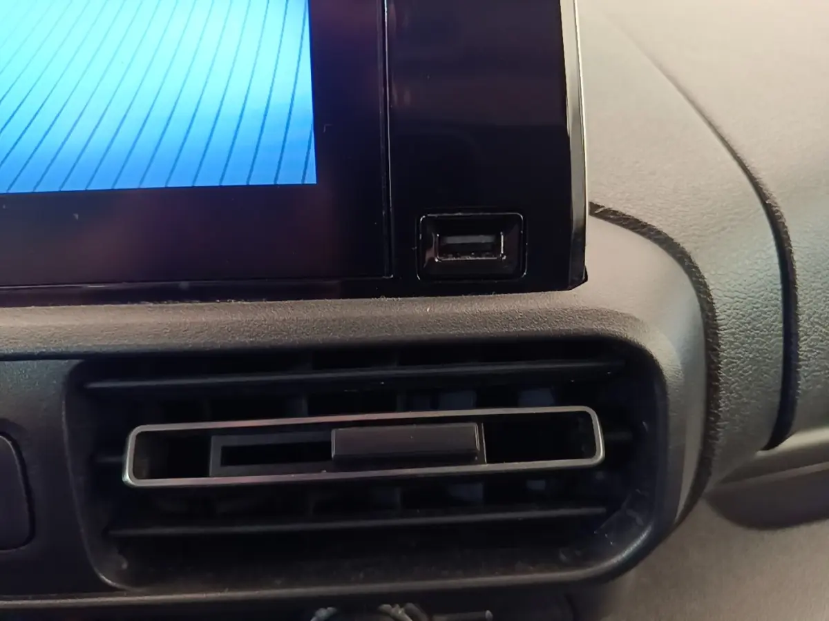 Gros plan sur la prise USB et la sortie d'aération du tableau de bord du Toyota Proace City Verso électrique gris clair.