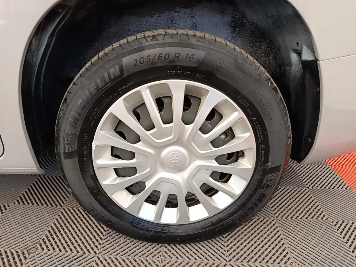 Gros plan sur la roue avant droite d’un Toyota Proace City Verso gris clair avec jante acier et enjoliveur plastique.
