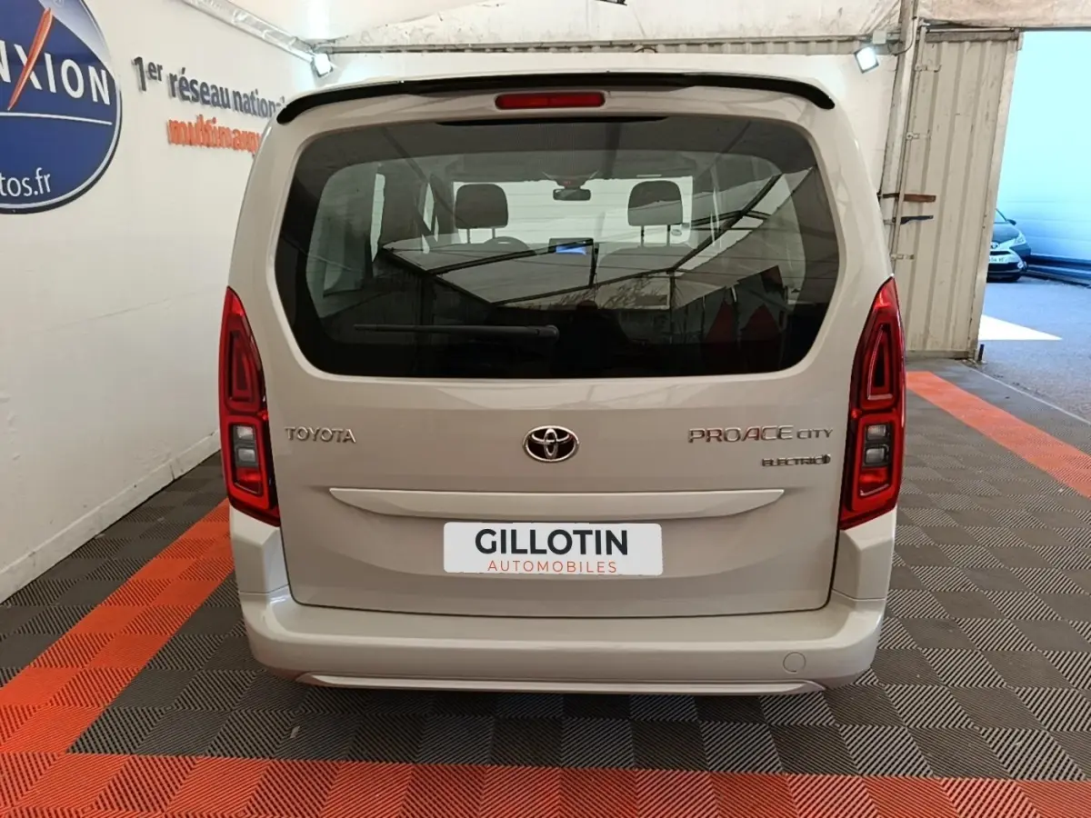 Vue arrière d’un Toyota Proace City Verso gris clair électrique, avec feux arrière rouges et vitre arrière large.