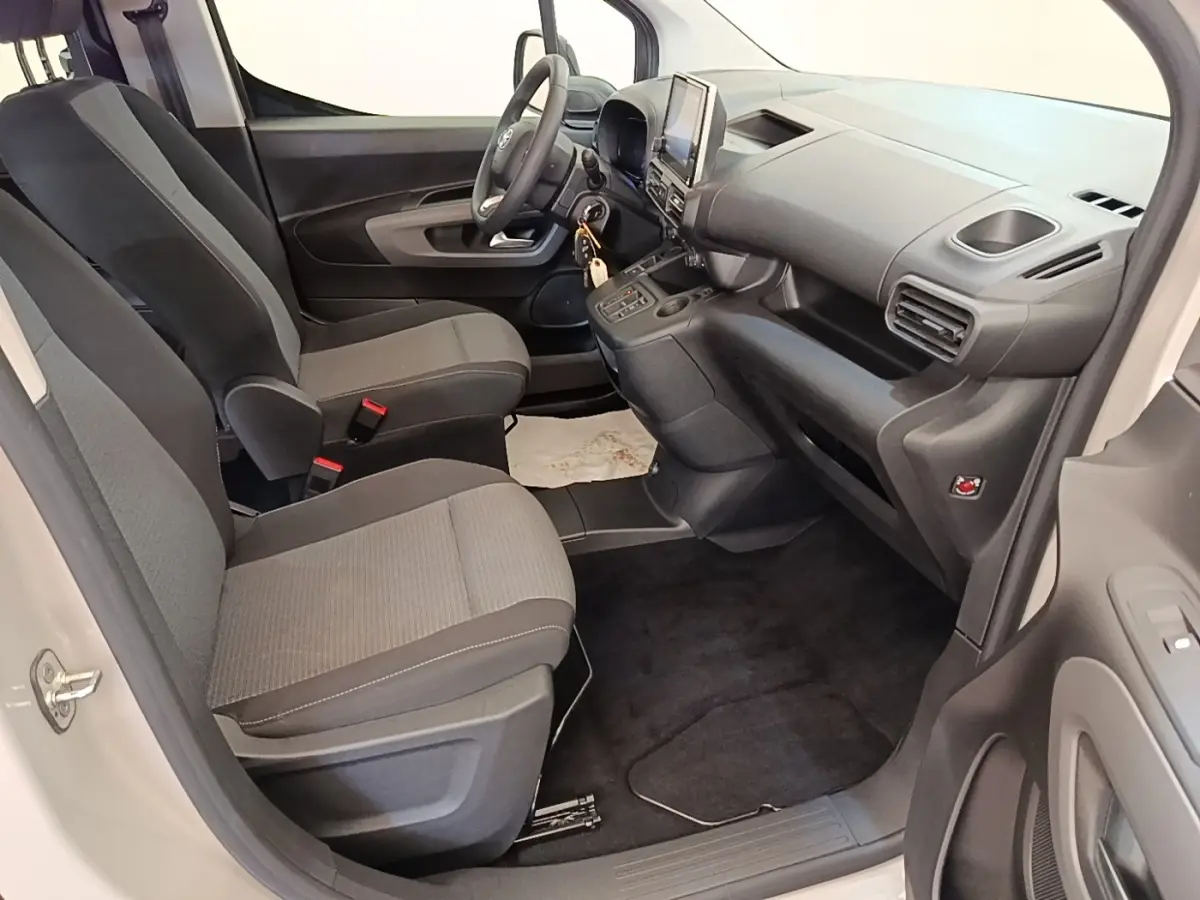 Vue intérieure côté conducteur du Toyota Proace City Verso électrique gris clair, avec tableau de bord et sièges en tissu gris.