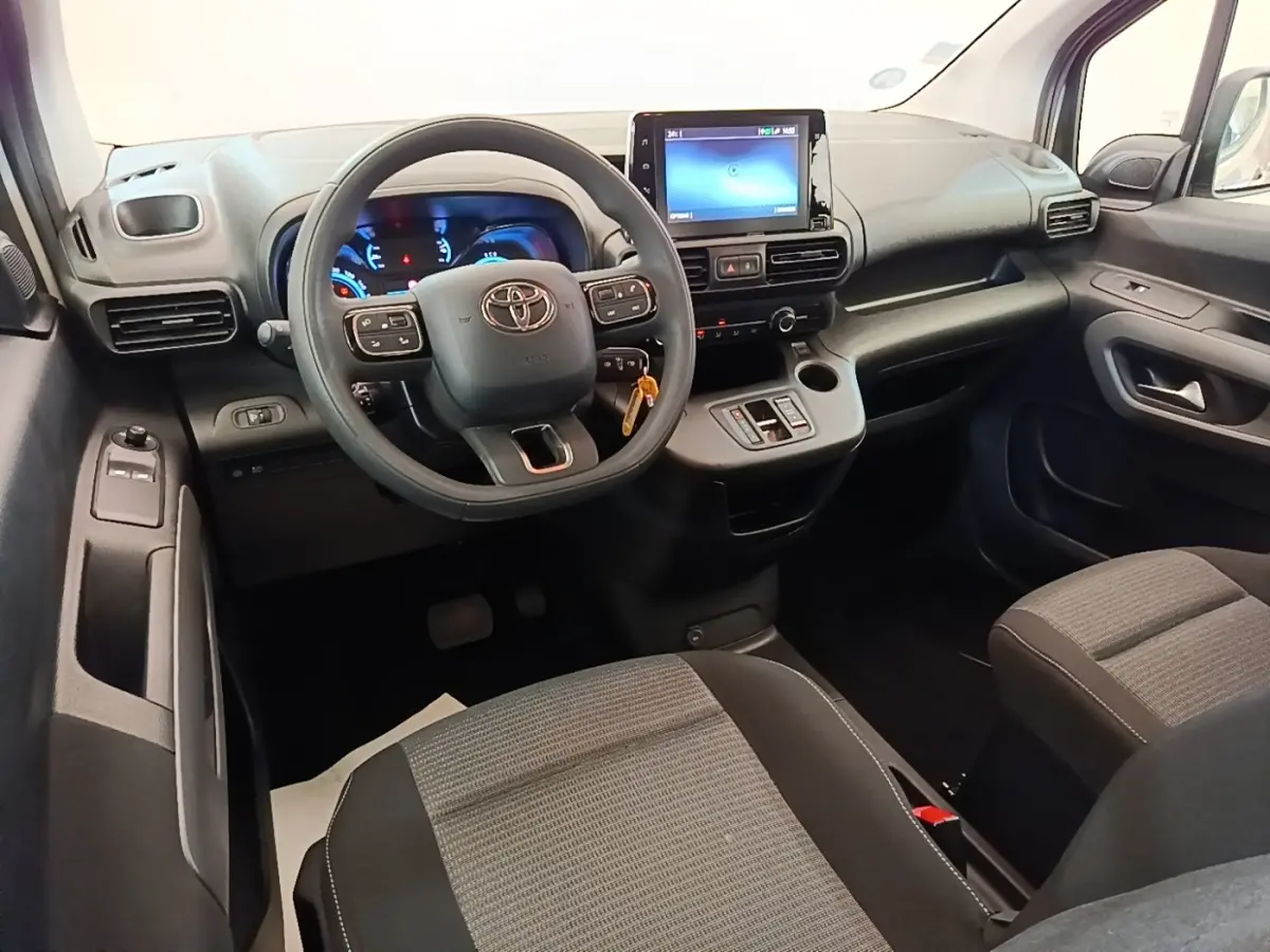 Vue intérieure avant du Toyota Proace City Verso 2022, tableau de bord noir avec écran tactile central et volant multifonction.