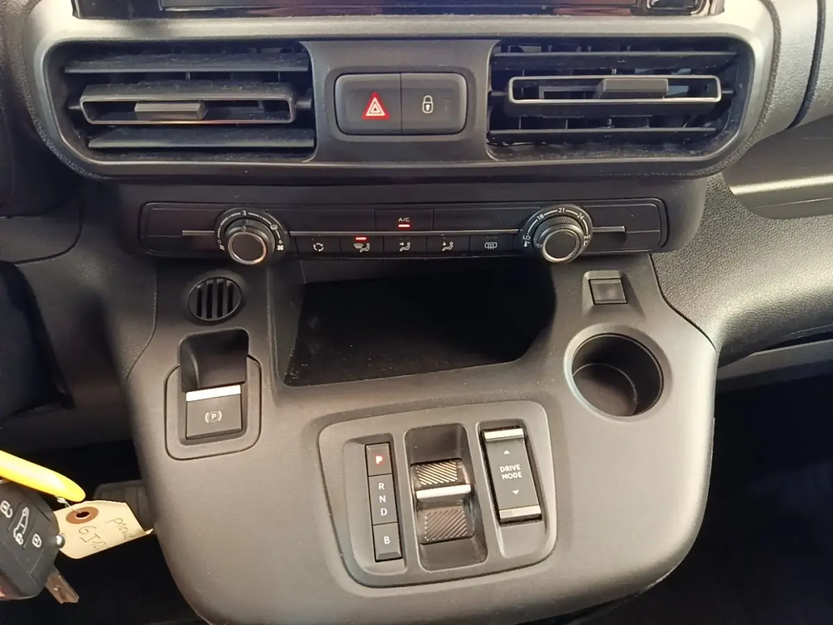 Vue rapprochée de la console centrale noire du Toyota Proace City Verso électrique, avec commandes de climatisation et boîte auto.