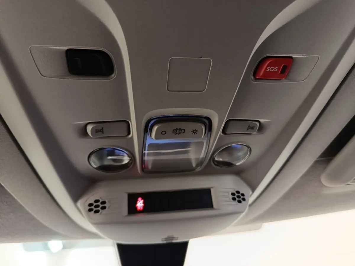 Vue en gros plan du panneau de commande de toit intérieur gris clair du Toyota Proace City Verso électrique avec bouton SOS rouge.