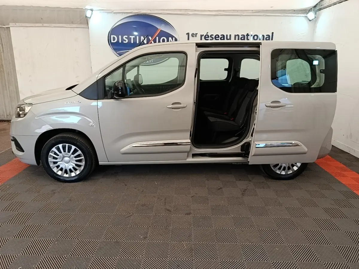 Vue latérale droite d'un Toyota Proace City Verso électrique gris clair avec porte coulissante arrière ouverte.