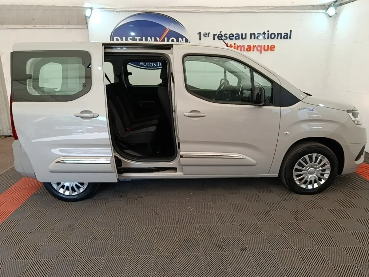 Vue de profil côté droit d'un Toyota Proace City Verso électrique gris clair avec porte coulissante arrière ouverte.