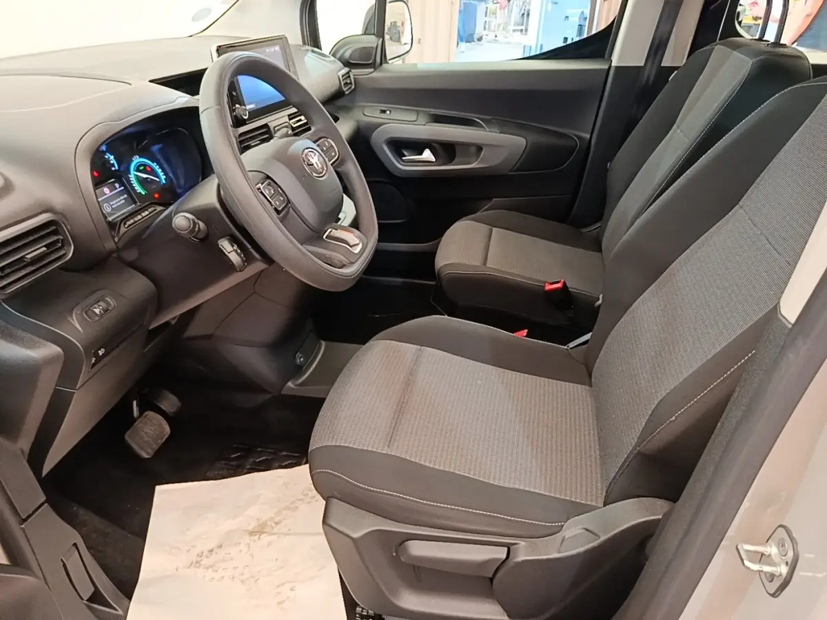 Vue intérieure côté conducteur du Toyota Proace City Verso électrique 2022, sièges gris et tableau de bord moderne.