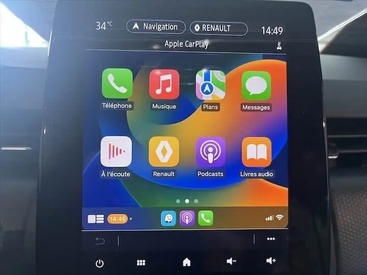 Écran tactile central de la Renault Clio V blanc nacré, affichant Apple CarPlay avec icônes colorées en vue frontale.