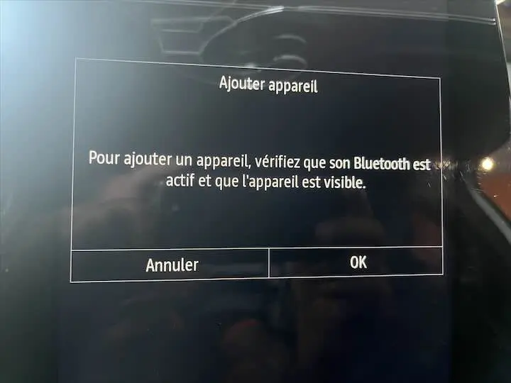 Écran tactile intérieur de la Renault Clio V blanc nacré métal affichant un message d'ajout d'appareil Bluetooth.