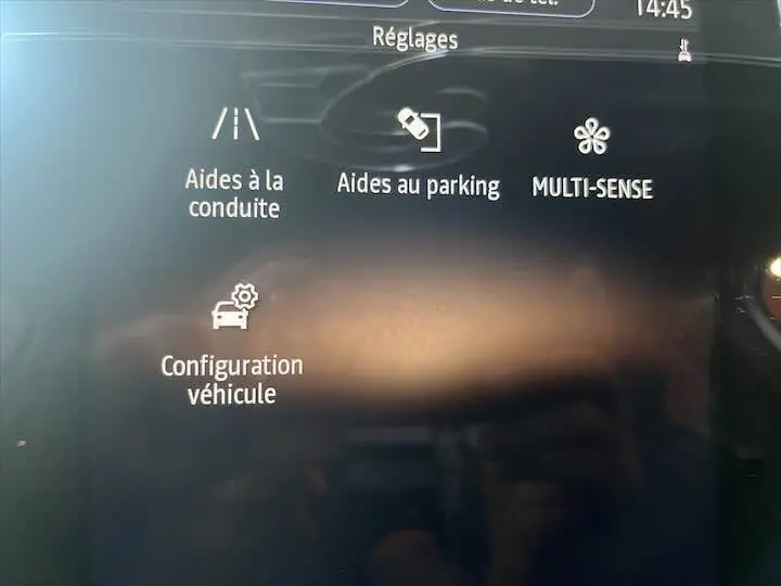 Écran tactile intérieur de la Renault Clio V blanc nacré, affichant les réglages d'aides à la conduite et parking.