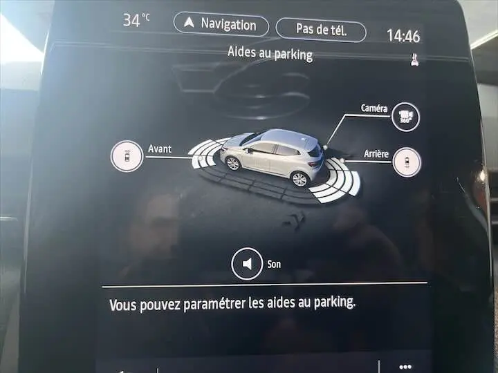Affichage intérieur de l'aide au parking avec vue 3D d'une Renault Clio V blanc nacré sur l'écran tactile.