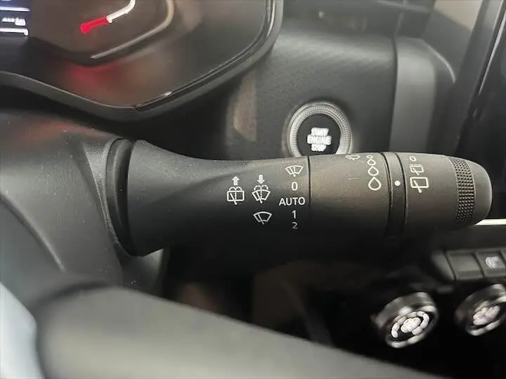 Gros plan sur la commande d'essuie-glace noire dans l'habitacle d'une Renault Clio V blanc nacré.