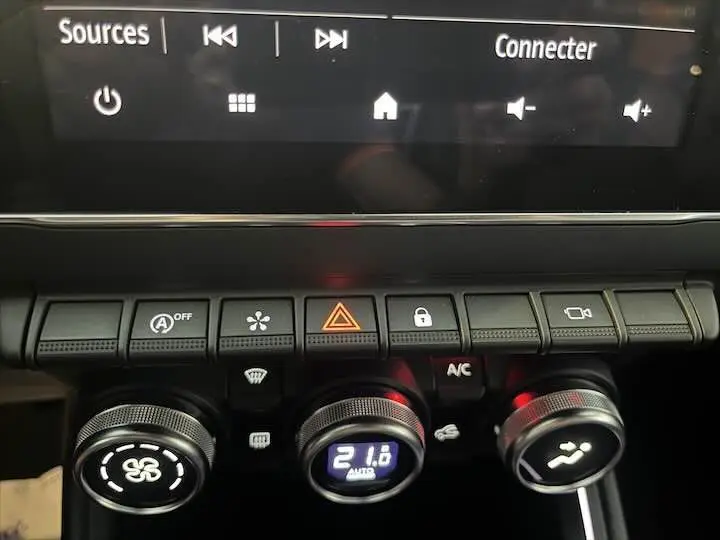 Détail du tableau de bord de la Renault Clio V avec commandes climatisation et boutons fonctionnels éclairés.