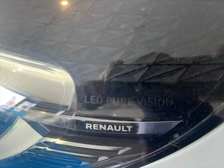 Gros plan sur le phare avant droit blanc nacré de la Renault Clio V avec logo Renault et inscription LED Pure Vision.