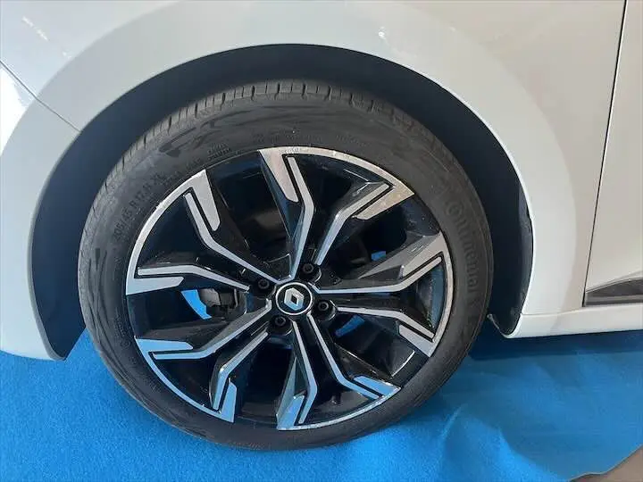 Gros plan sur la roue avant droite d'une Renault Clio V blanc nacré métal avec jante alliage noire et argentée.
