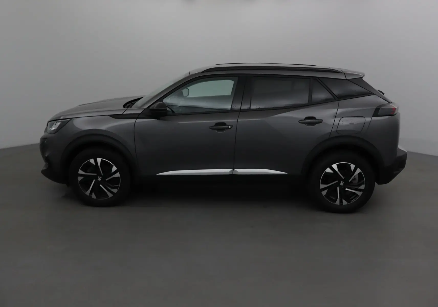 Profil côté gauche du Peugeot 2008 gris platinium 2022 avec jantes alliage et lignes modernes marquées.