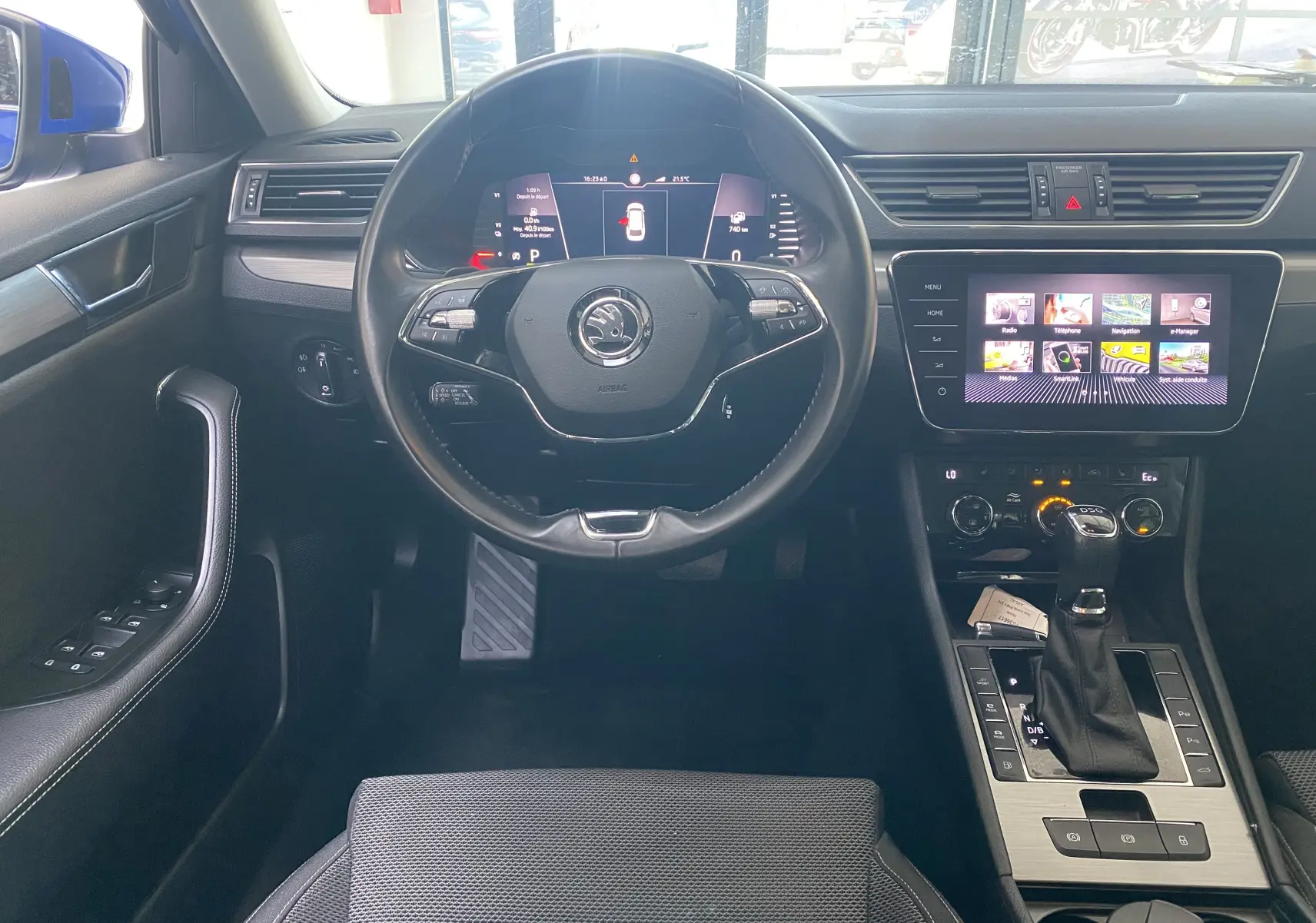 Vue intérieure avant du Skoda Superb Combi bleu énergie, tableau de bord numérique et console centrale avec écran tactile.