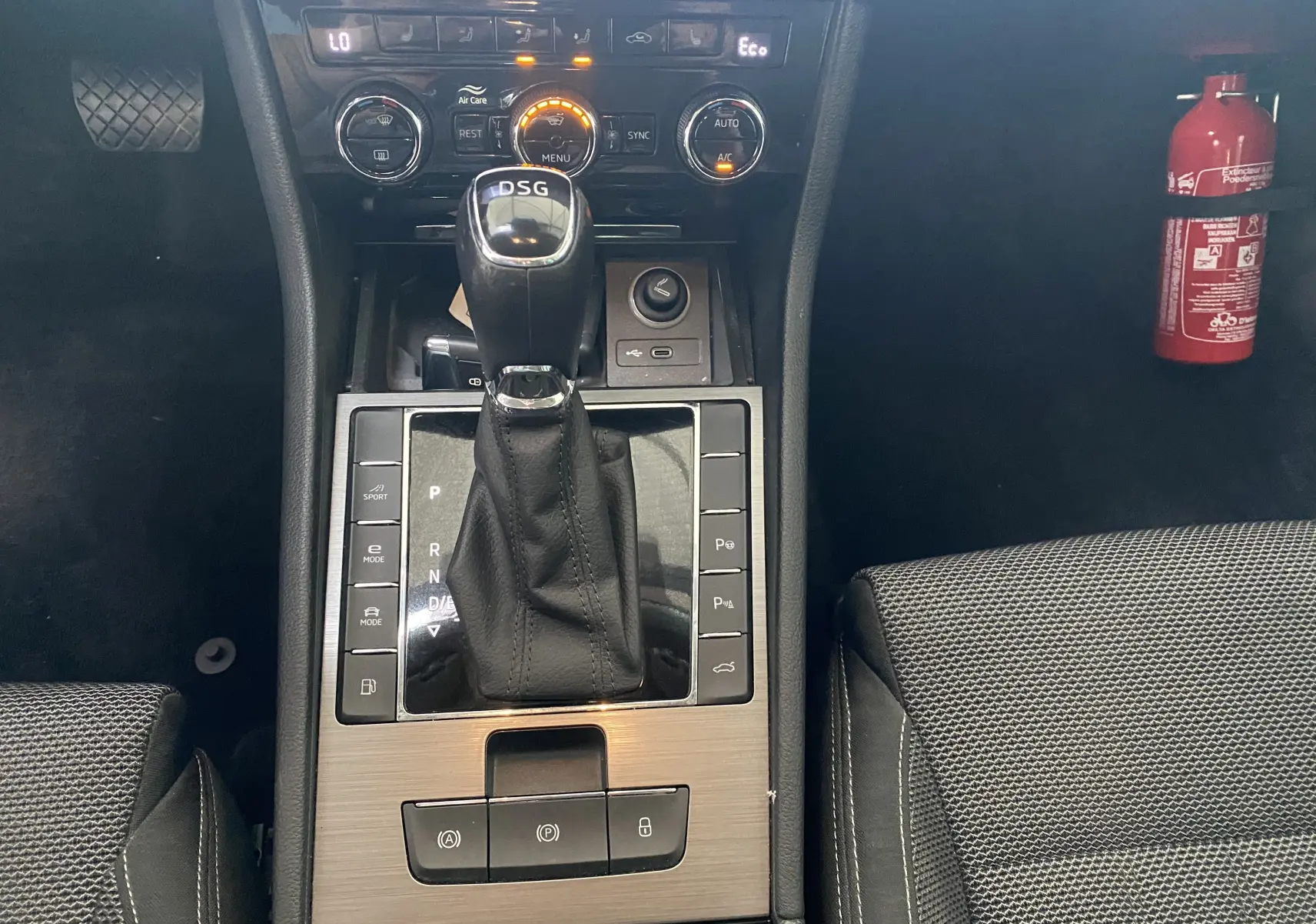Vue rapprochée de la console centrale de la Skoda Superb Combi IV avec levier DSG et commandes de climatisation allumées.