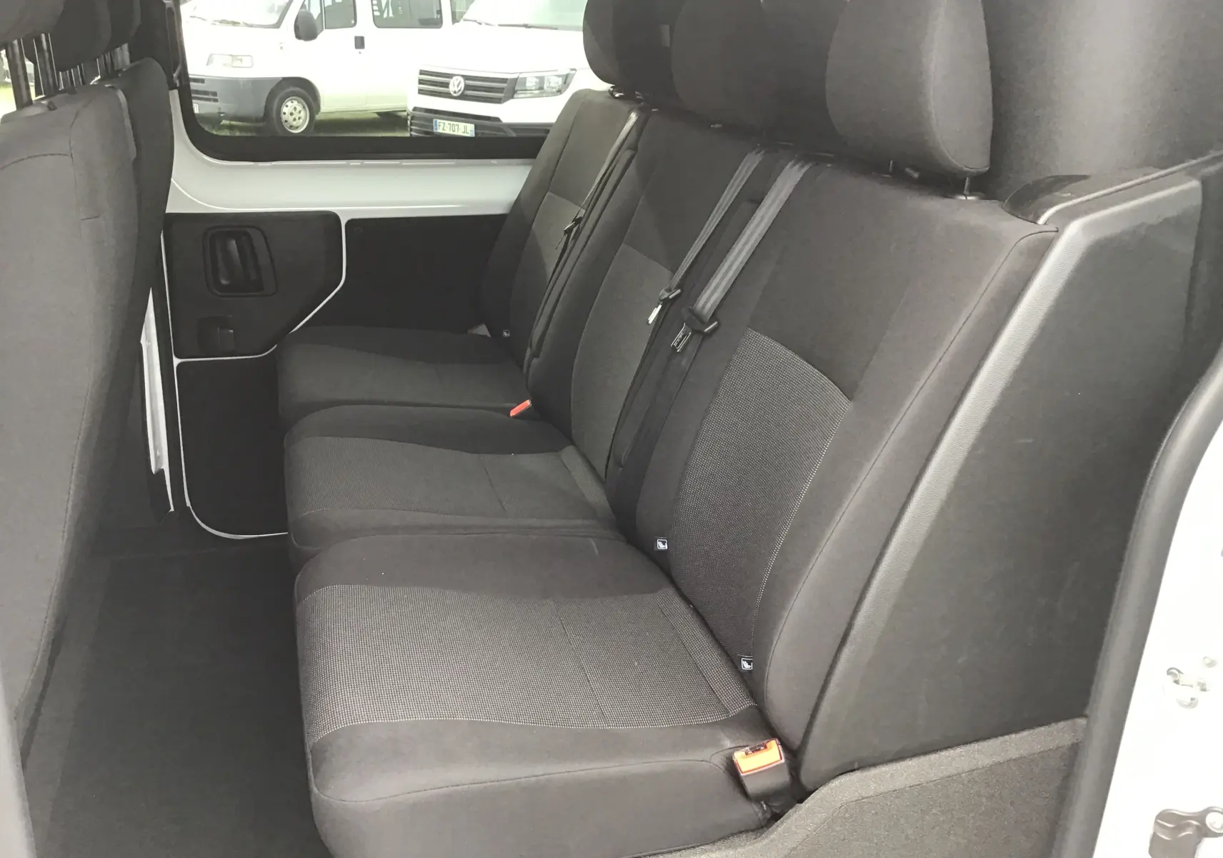 Vue intérieure côté droit des sièges arrière noirs du Citroën Jumpy Cabine Approfondie blanc, avec ceintures de sécurité visibles.