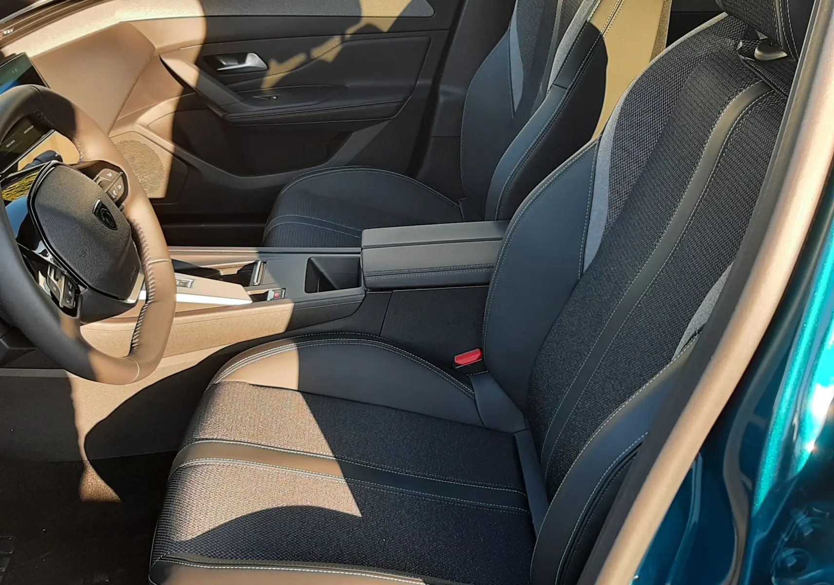 Intérieur avant droit de la Peugeot 308 Bleu Obsession 2025, sièges noirs avec surpiqûres claires et console centrale moderne.