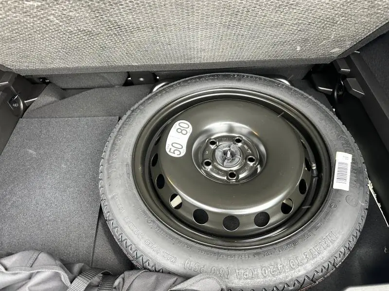 Roue de secours noire en gros plan dans le coffre du Renault Captur 2025 hybride, vue de dessus.