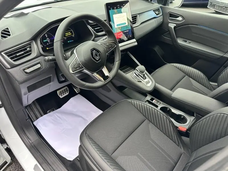 Vue intérieure côté conducteur du Renault Captur 2025 esprit Alpine, avec tableau de bord moderne et sièges noirs en tissu.