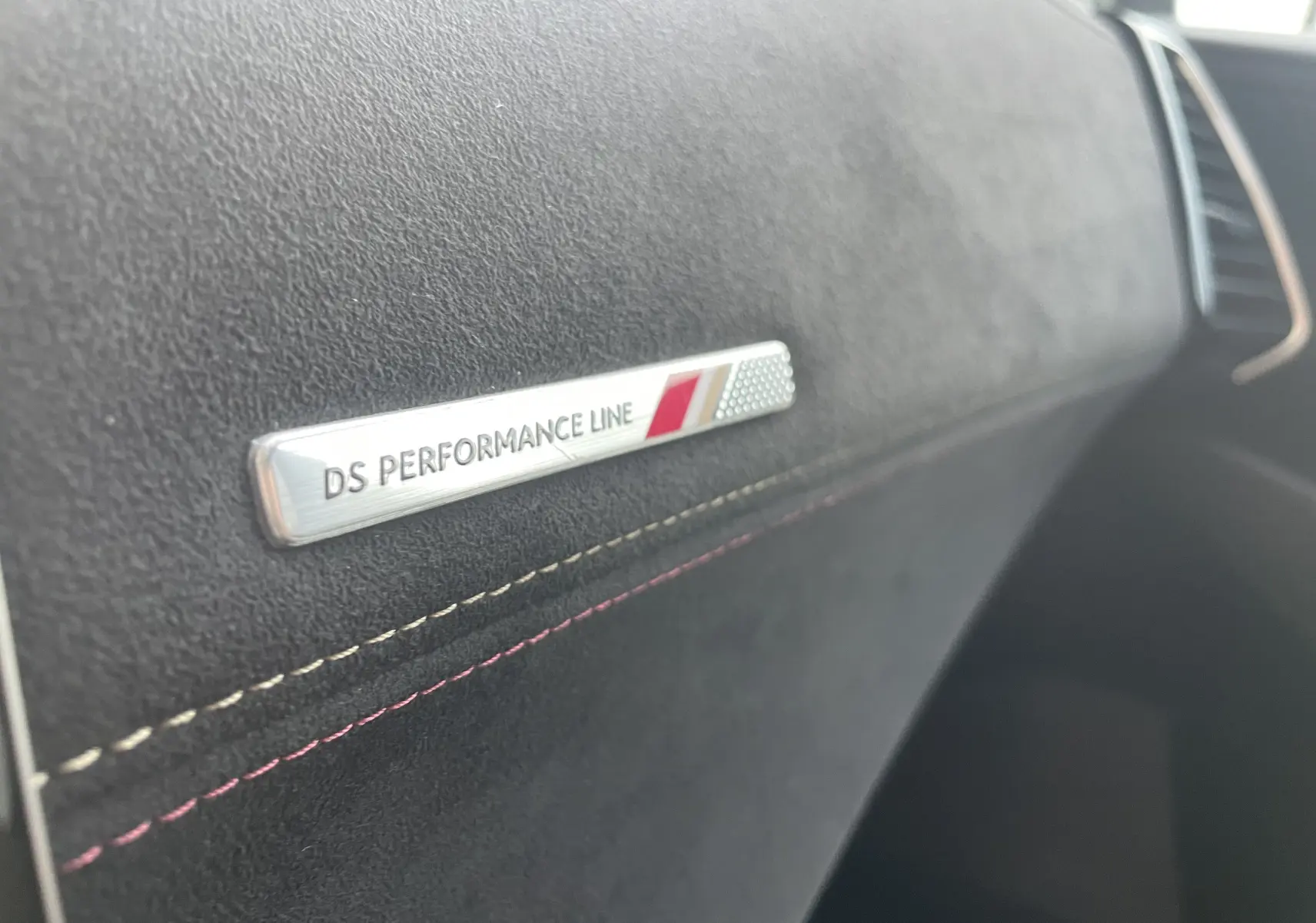 Gros plan sur l’inscription DS Performance Line sur la planche de bord en tissu gris noir du DS7 2021.