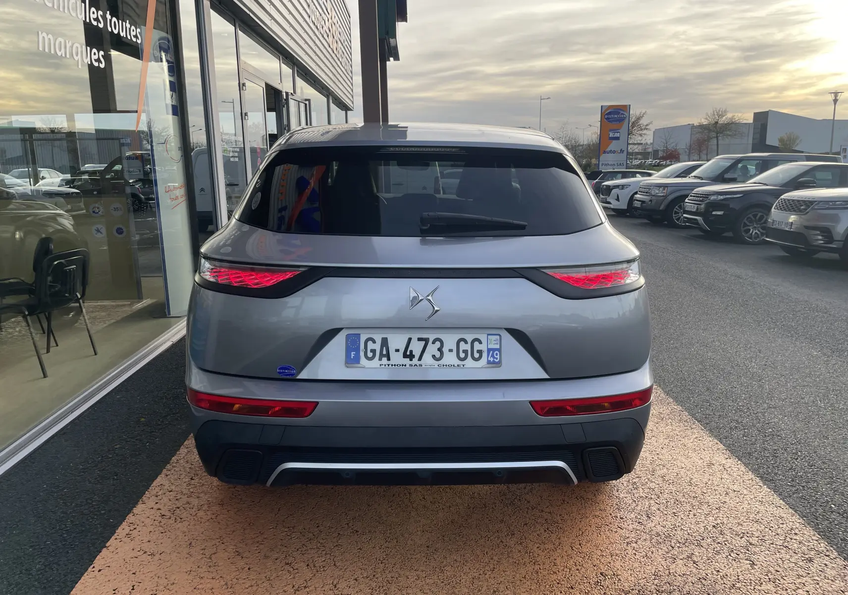 Vue arrière d'un DS7 gris avec feux LED distinctifs et plaque d'immatriculation française visible.