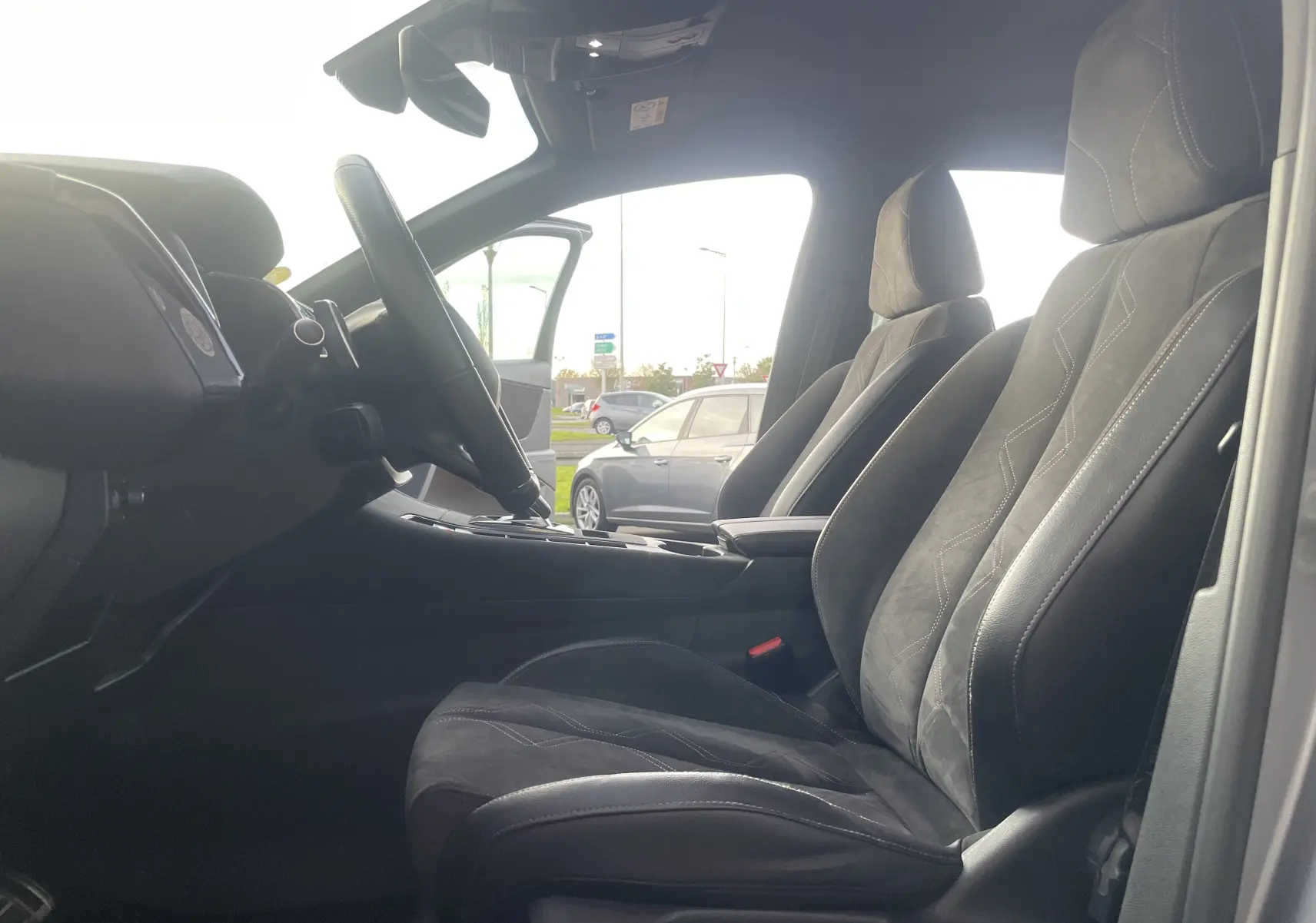 Intérieur du DS7 2021 en gris noir, vue côté conducteur sur les sièges avant et le volant multifonction.