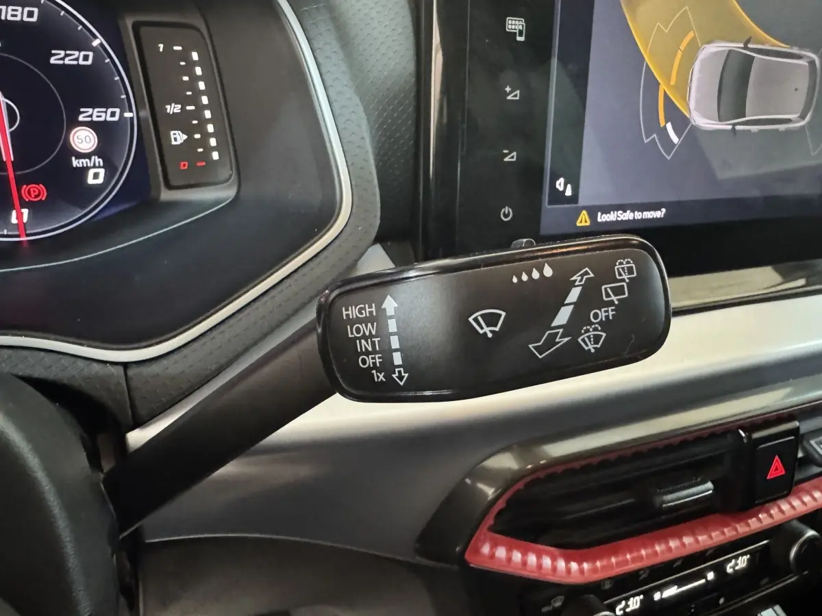 Le levier d'essuie-glace avec pictogrammes, tableau de bord numérique et écran tactile dans l'habitacle de la SEAT Ibiza rouge 2024.