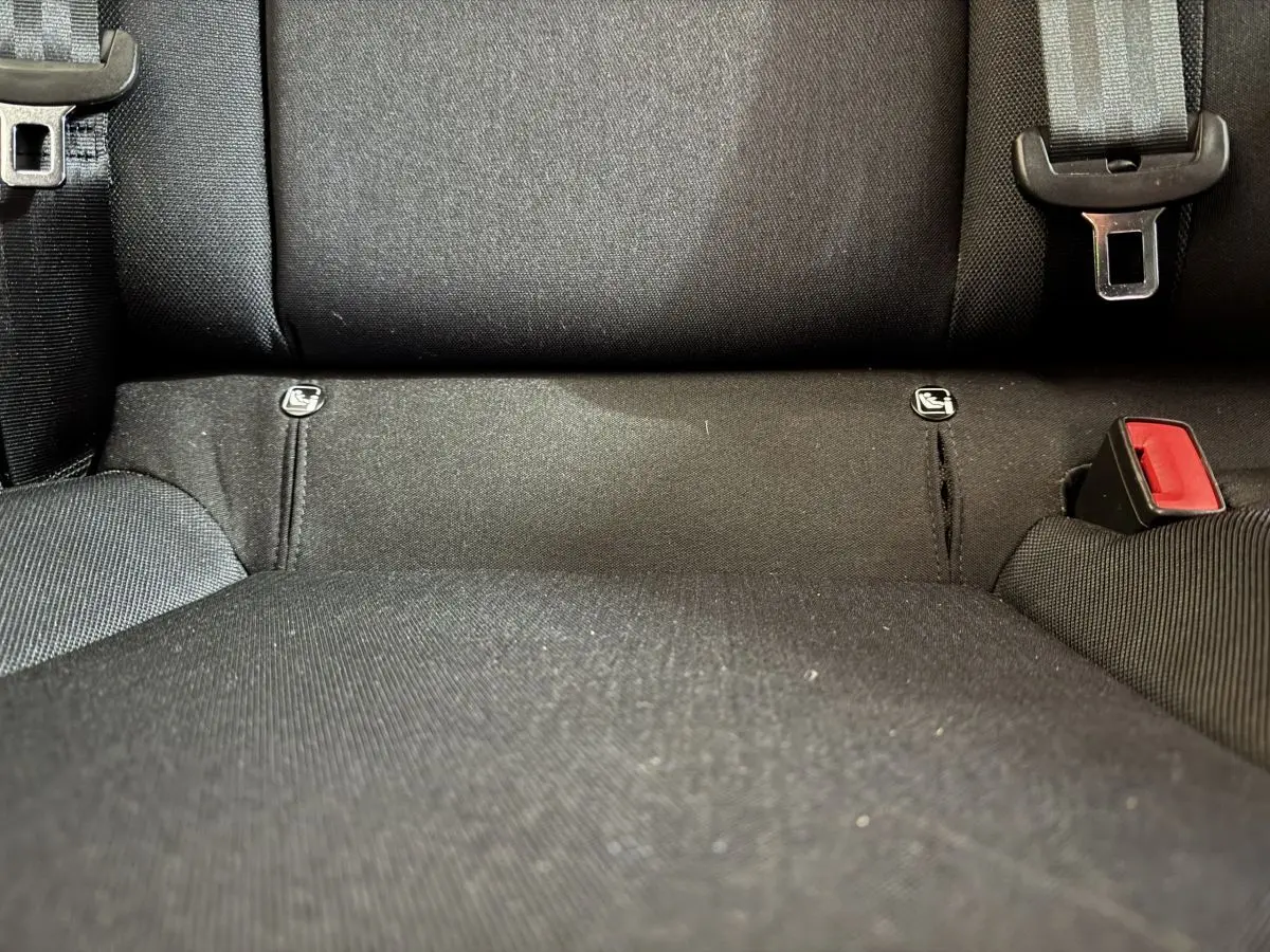 Gros plan sur la banquette arrière noire de la SEAT Ibiza 2024 avec attaches Isofix et boucle de ceinture rouge.