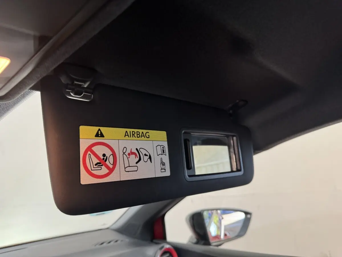 Détail du pare-soleil côté conducteur avec miroir et avertissement airbag dans une SEAT Ibiza rouge 2024.