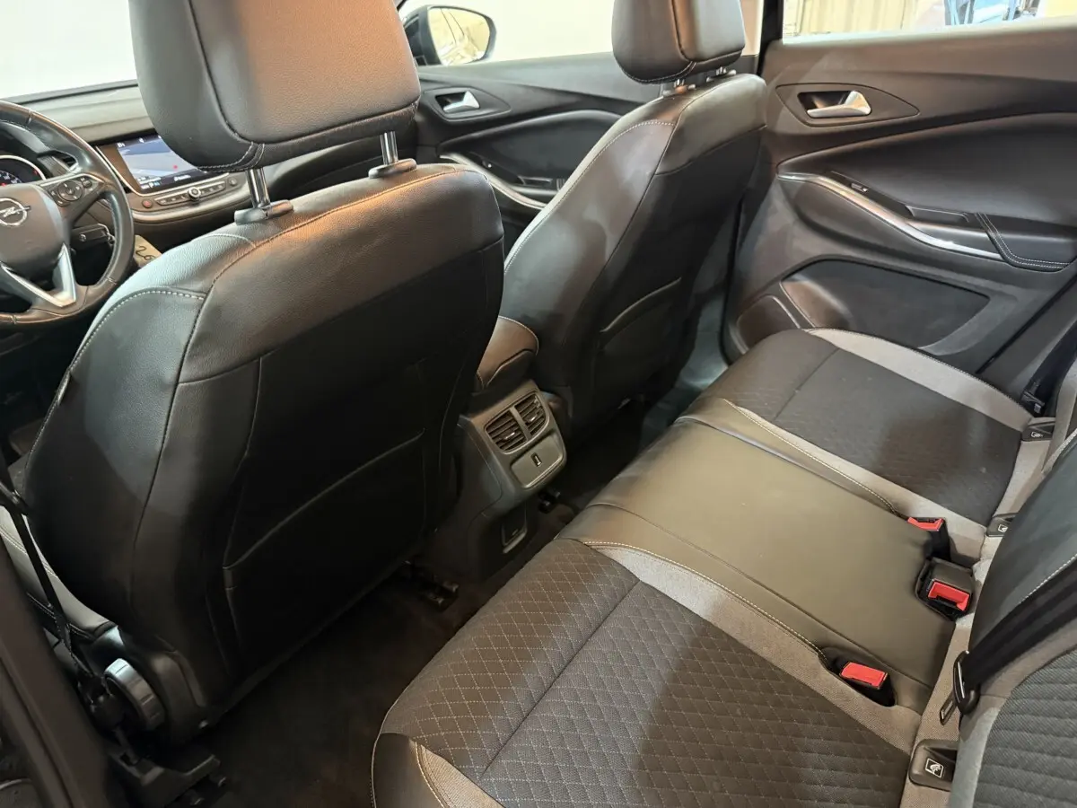 Vue intérieure arrière côté droit du Opel Grandland X 2021 avec sièges en cuir et tissu noirs et console centrale avec aérateurs.