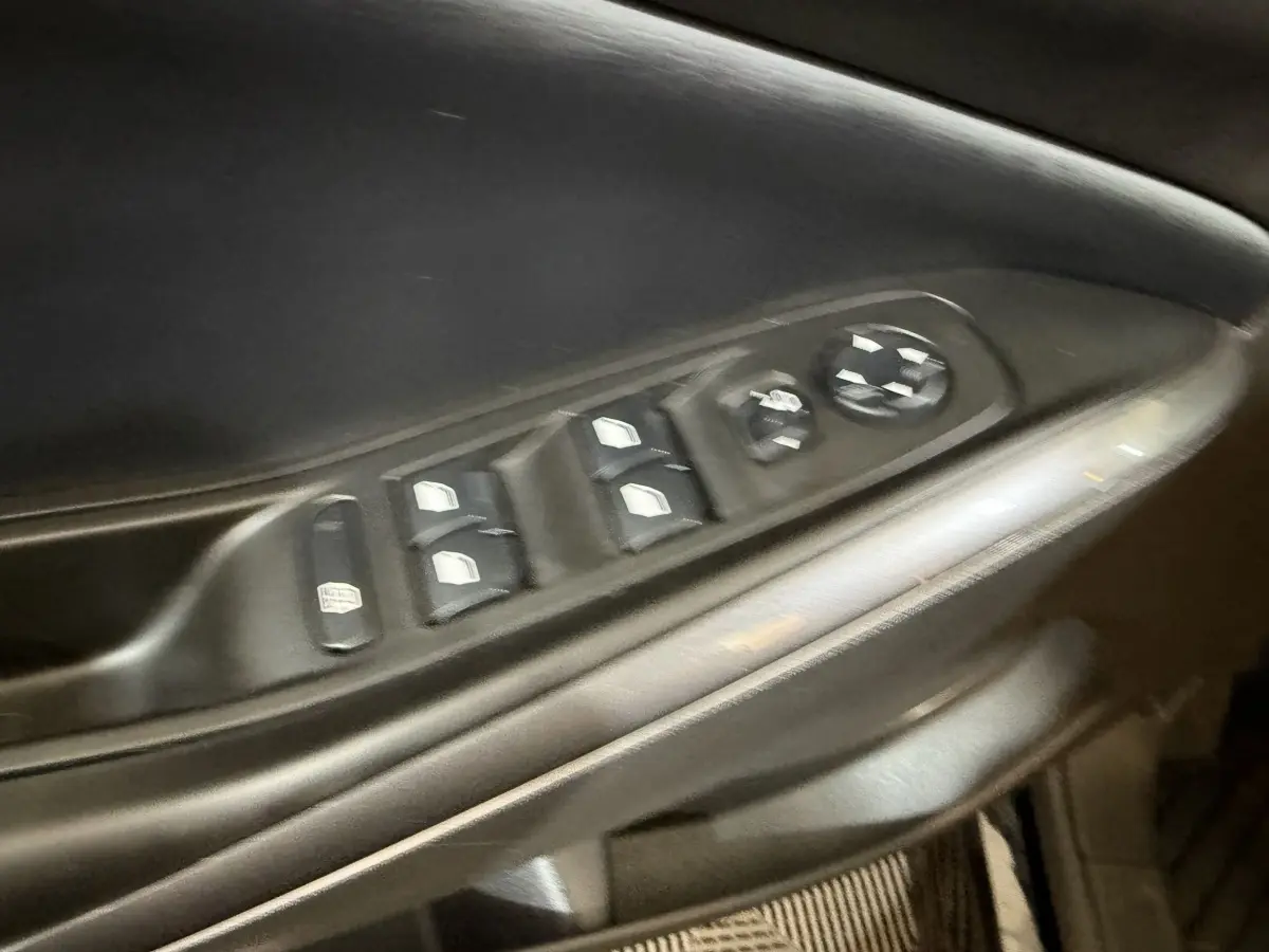 Gros plan sur la commande des vitres électriques et réglages des rétroviseurs côté conducteur de l’Opel Grandland X noir.