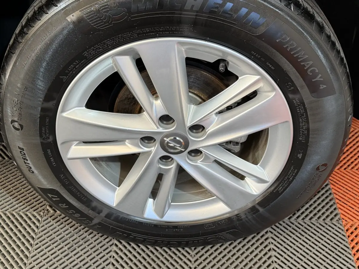 Gros plan sur la jante argentée et le pneu Michelin d’un Opel Grandland X noir, vue de face.