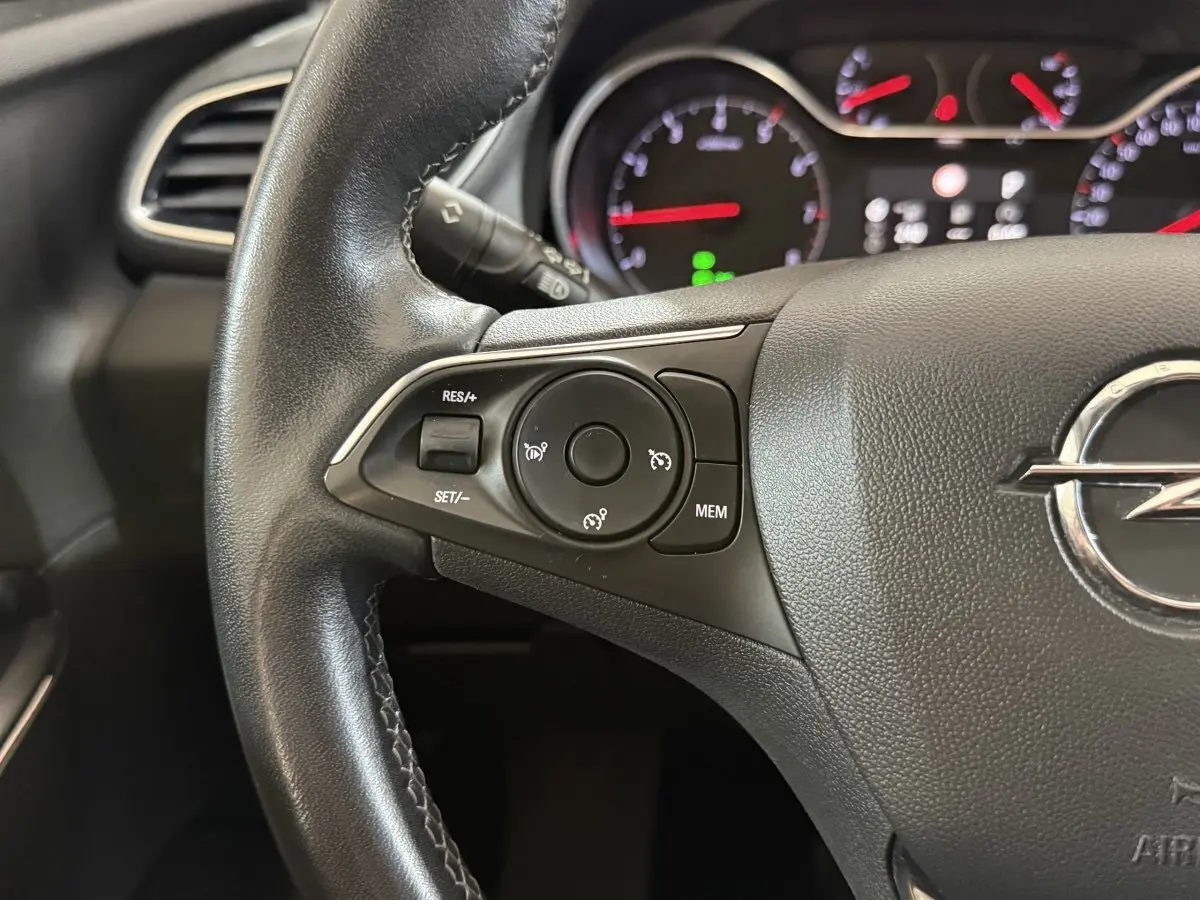 Gros plan sur le volant cuir noir de l'Opel Grandland X 2021 avec commandes de régulateur de vitesse et tableau de bord lumineux.
