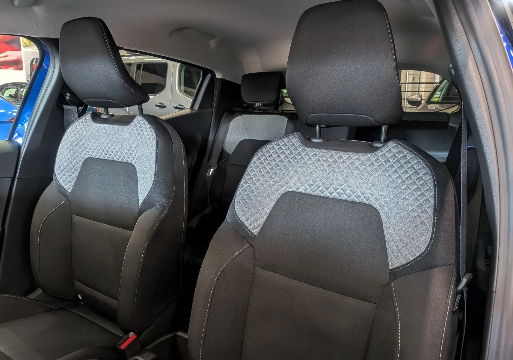 Vue intérieure des sièges avant en tissu noir et gris de la Renault Clio V Bleu Iron, version Evolution + Pack Look.