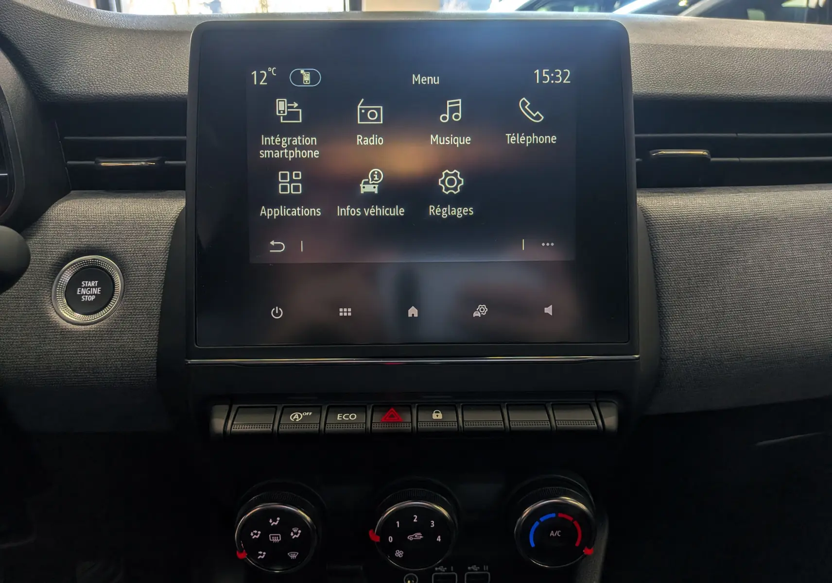 Vue rapprochée de l’écran tactile central et des commandes de climatisation de la Renault Clio V Bleu Iron, intérieur tissu noir.