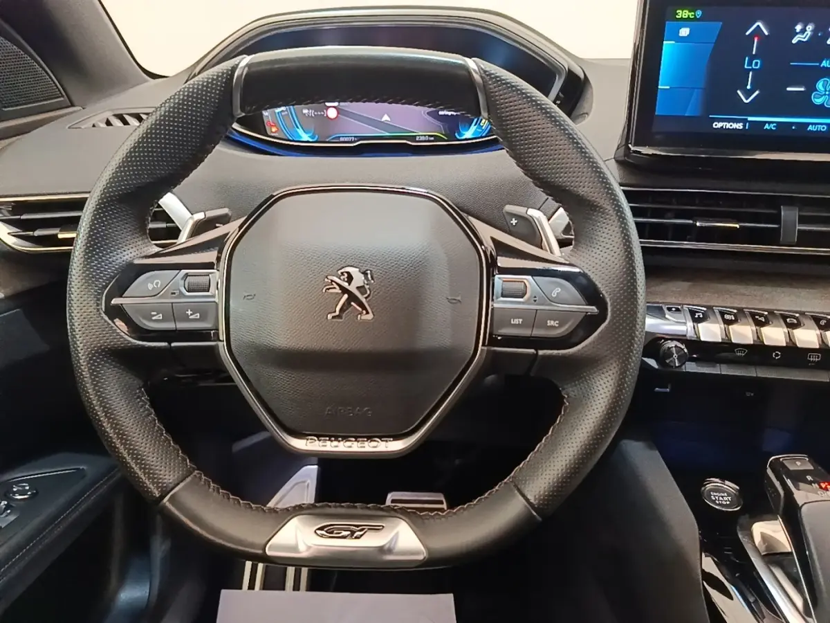 Vue rapprochée du volant cuir noir GT de la Peugeot 3008 hybride avec tableau de bord digital et console tactile.