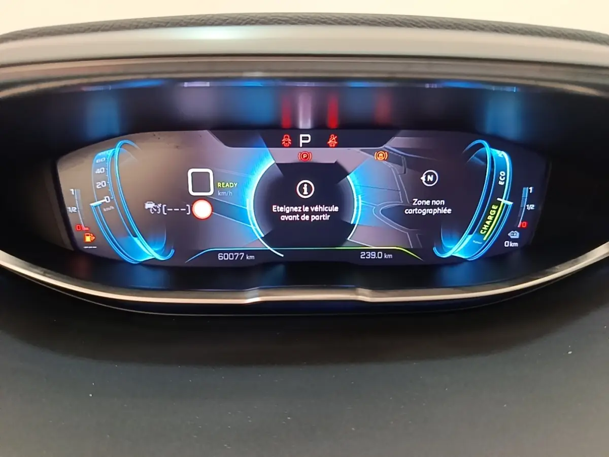 Vue rapprochée du tableau de bord numérique bleu du Peugeot 3008 Hybrid 225 GT affichant 60 077 km et messages d'alerte.
